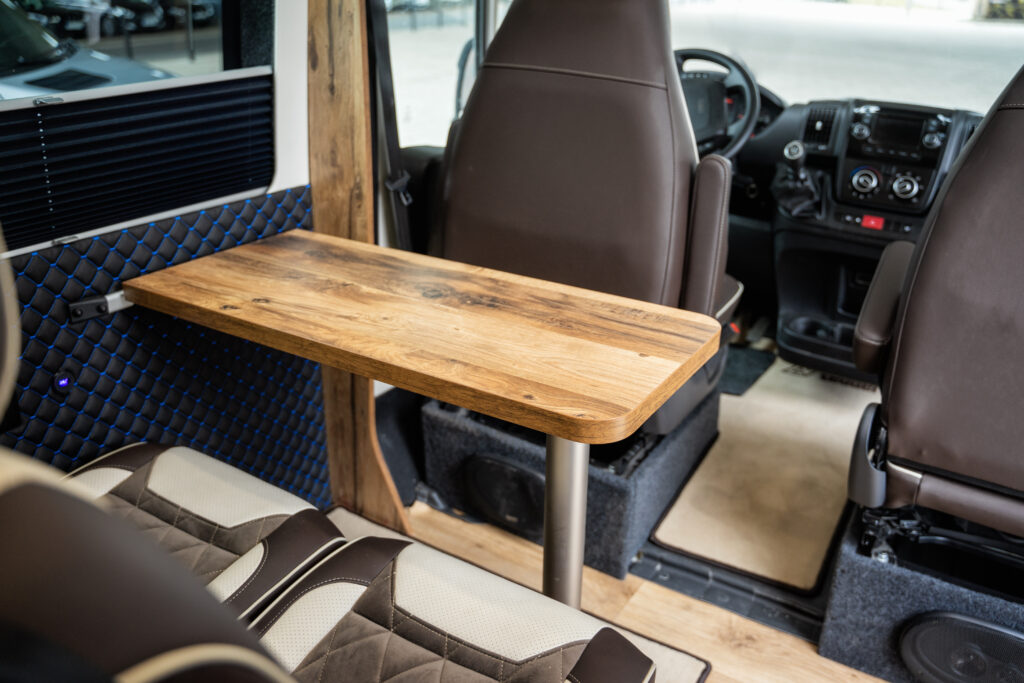 Wnętrze kampera z drewnianym stołem rozkładanym.