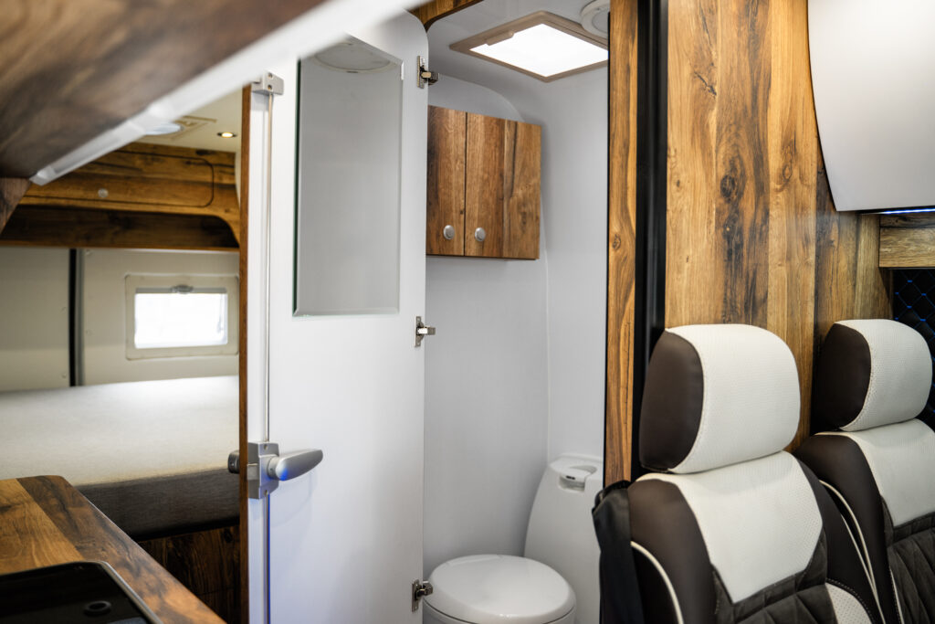 Wnętrze kampera z łazienką, drewniane wykończenia.