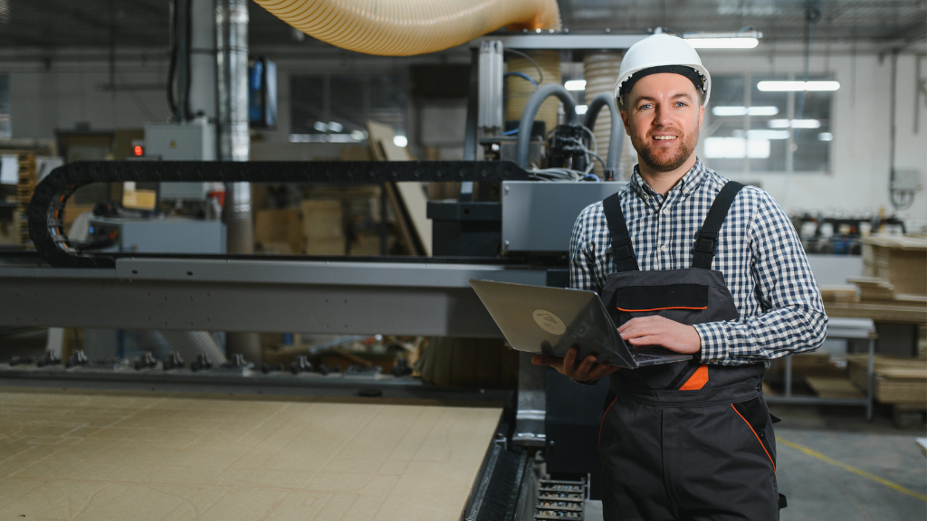 Pracownik w fabryce z laptopem i kaskiem
