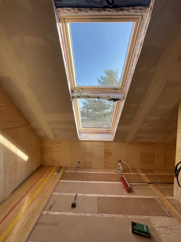 Poddasze z oknem dachowym, widok na niebo.