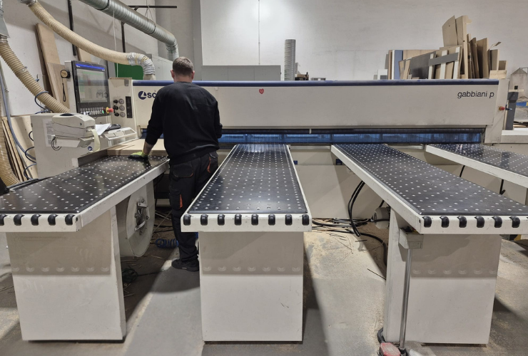 Pracownik obsługujący maszynę do cięcia drewna.